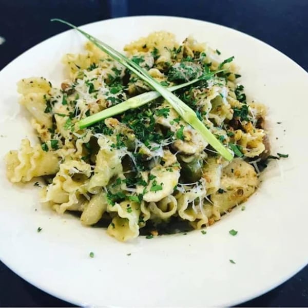 Capp's Pizzeria & Trattoria's pasta dish with ruffled edges, topped with cheese, herbs, and green garnish.