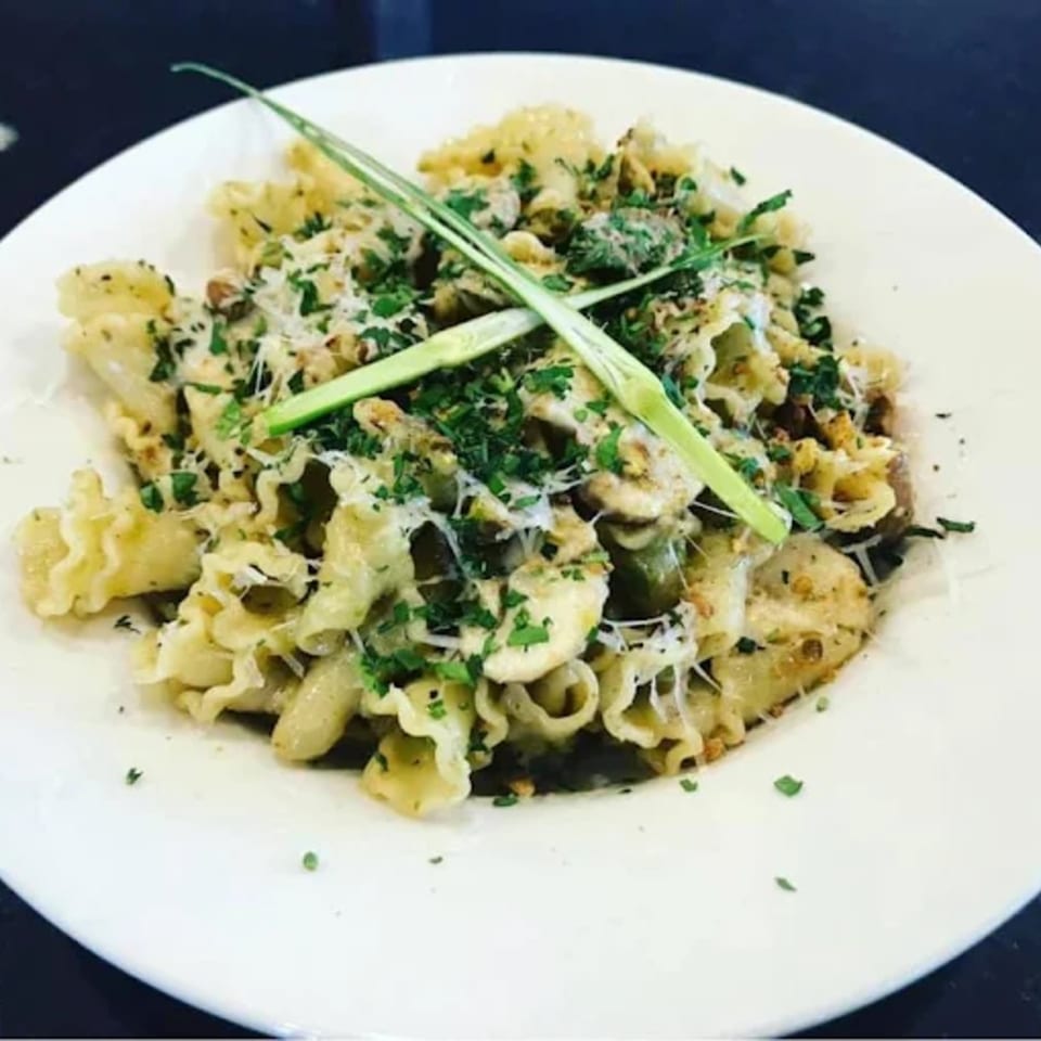 Capp's Pizzeria & Trattoria's pasta dish with ruffled edges, topped with cheese, herbs, and green garnish.