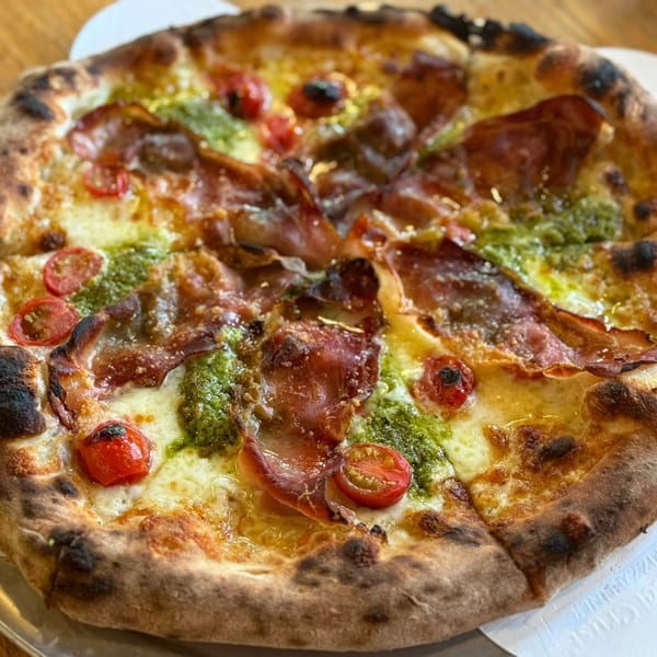 A Capp's Pizzeria pizza with prosciutto, pesto, cherry tomatoes, and melted cheese.